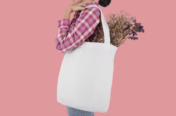 Kız çantası kanvas kumaş çiçek, pembe arka plan izole mockup boş şablon için tutuyor. 