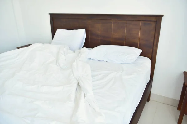 white bedding sheets and pillow in white bedroom hotel. Messy and crumpled bed concept.