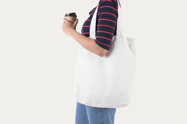 女の子は 白い背景で隔離のモックアップ空白テンプレートのバッグ キャンバス生地を保持しています — ストック写真