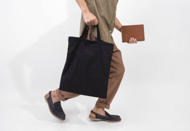 Holding siyah çanta tuval kumaş mockup boş şablon gri arka plan üzerinde izole için adamdır. 