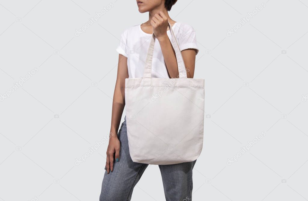 Girl is holding bag canvas fabric for mockup blank template isolated on gray background.