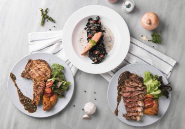 domuz eti biftek sığır eti biftek ve somon siyah beyaz plaka üzerinde tablo Restoran makarna. üstten görünüm.