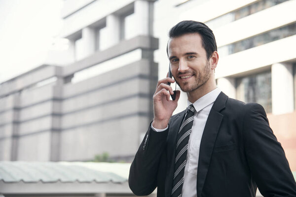 Красивый бизнесмен разговаривает по мобильному телефону.