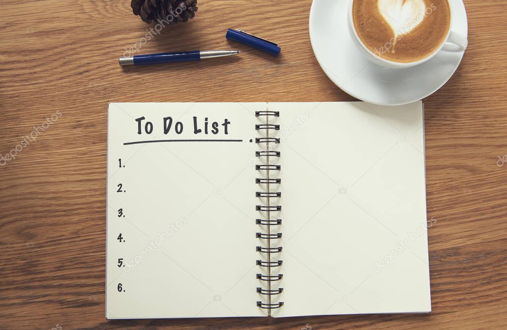 Coffee cup and notebook with to do list on rustic desk from above, planner and checklist concept.