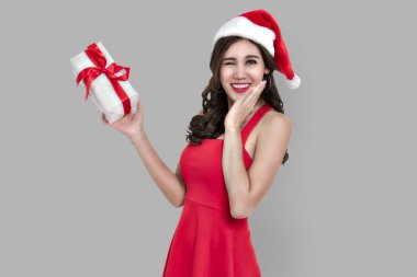 Neşeli genç kadın kırmızı elbise gri arka plan üzerinde izole Noel için hediye kutusu tutarak santa.
