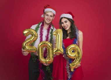 Portre genç çift altın taşıyan numaraları 2019 kırmızı arka plan üzerinde renkli. kutlama Noel ve mutlu yeni yıl kavramı. 