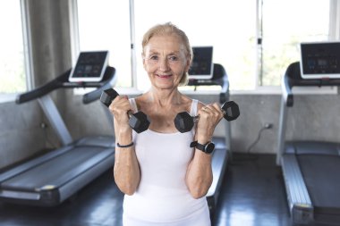 Kadın kıdemli egzersiz fitness salonunda halter kaldırma.