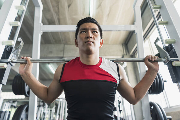 Young asian man lifting barbell in gym. healthy lifestyle and workout motivation concept.