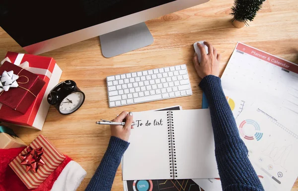 Businesswoman writing to do list in christmas holiday at the office with christmas decoration on table.