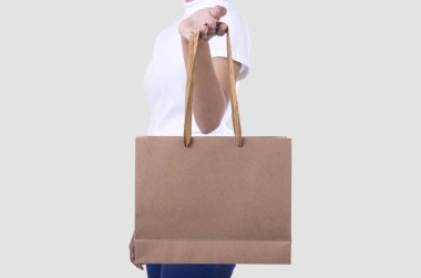 Holding boş kahverengi kağıt alışveriş çantası mockup şablon reklam için el ve marka beyaz arka plan üzerinde izole. 