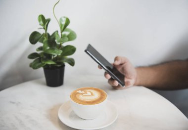 Akıllı telefon kahve kahve fincanı kahve dükkanında, günlük yaşam tarzı ile sosyal medya kullanarak ele. 
