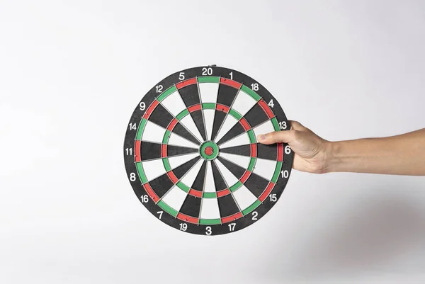 Hand holding target dart board on gray background.