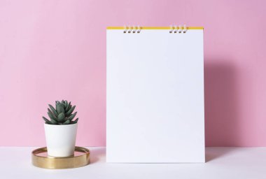 Kaktüs pembe bir arka plan üzerinde olan mockup kağıt sarmal takvimi.  