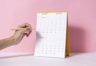 Kağıt sarmal takvim üzerinde yazma işaretleme için kalem tutan el