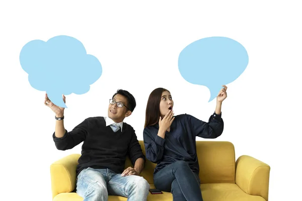 Молодой человек и женщина сидят на диване, держа пузырь речи — стоковое фото