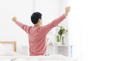 adam uyan ve sabah güneş doğarken penceresiyle yakınındaki kol germe