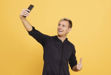 sarı üzerinde siyah smartphone üzerinde selfie alarak mutlu adam 