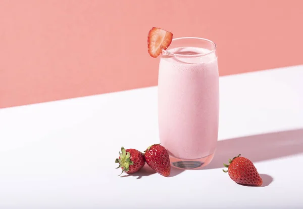 Smoothie de morango em vidro com palha e bagas espalhadas — Fotografia de Stock