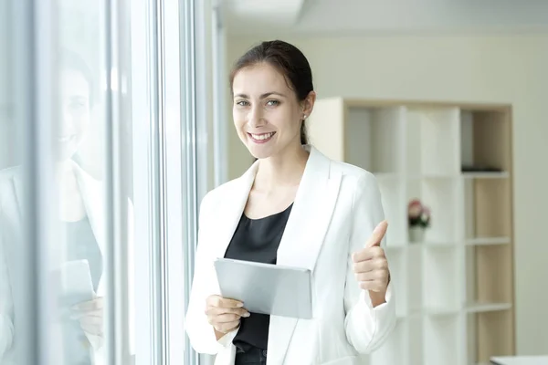 Happy business woman looking camera with stance thumb up.