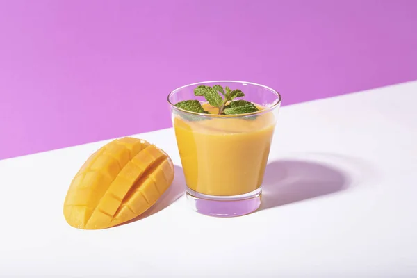 Smoothie de manga fresca e fatia de manga madura no fundo roxo . — Fotografia de Stock