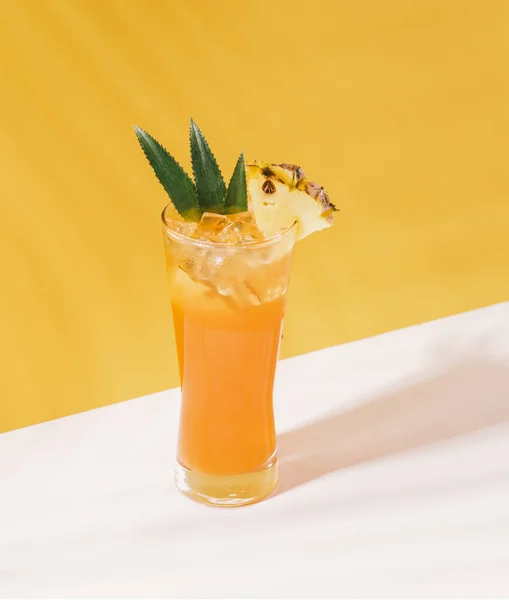 Iced pineapple punch cocktail in glass on orange background. — Stock Photo, Image