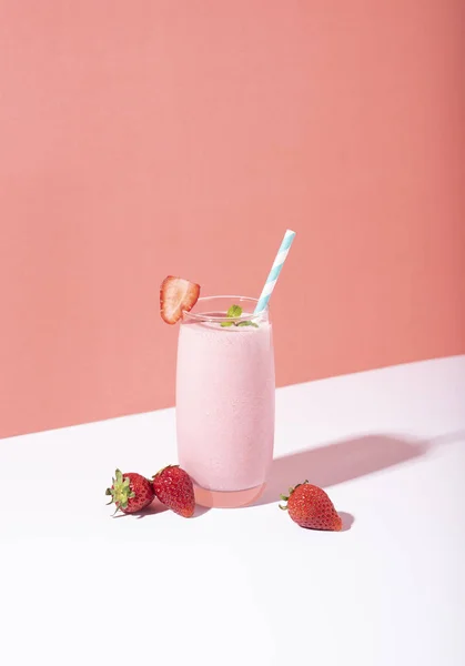 Полунична смугаста в склянці з соломою і розкиданими ягодами — стокове фото