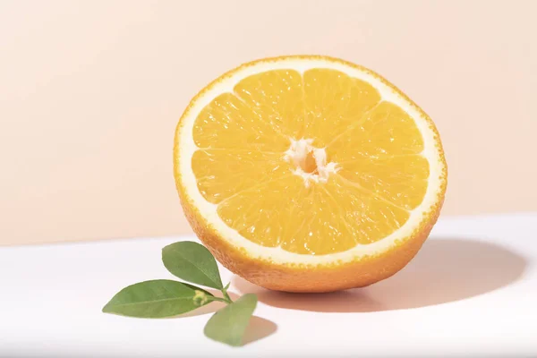 Slice orange fruit with orange leaf on color background.