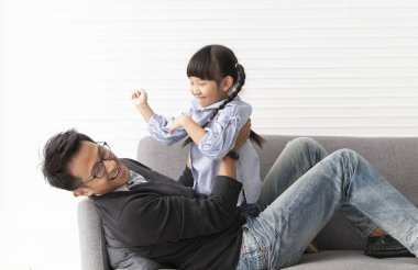 Asyalı baba ve kızı oturma odasında birlikte oynuyor 