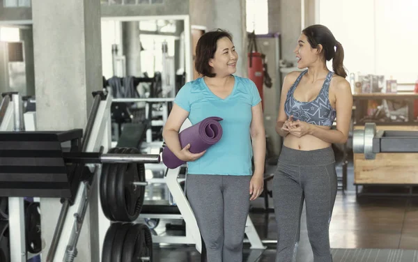 Happy asian couple senior and young woman holding yoga mats and walking in class of fitness gym. — Stock Photo, Image