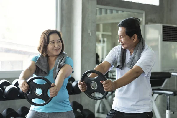 Asian senior man and woman exercise lifting dumbbell in fitness gym. elderly healthy lifestyle. — Stock Photo, Image