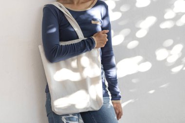 Kız güneş ışığı arka plan üzerinde mockup boş şablon için çanta tuval kumaş tutuyor. küresel ısınma kavramı.