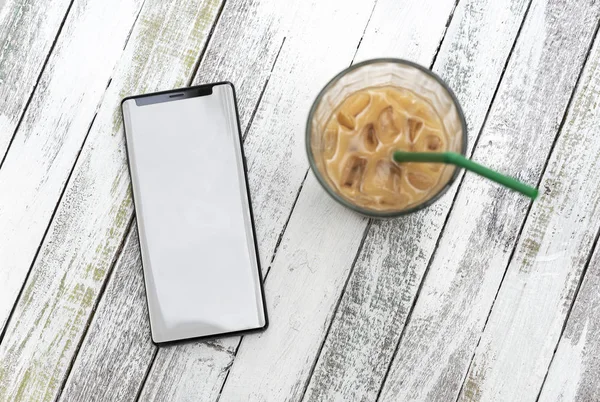 Изображение мобильного телефона с пустым экраном и чашкой кофе на деревянном столе в кафе . — стоковое фото