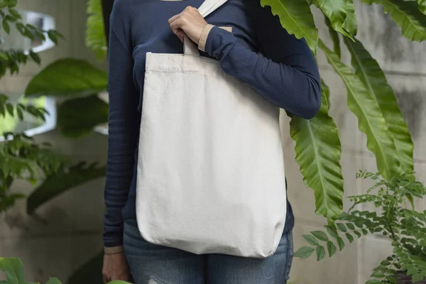 Chica está sosteniendo tela de lona bolsa para maqueta plantilla en blanco en el fondo de la naturaleza. concepto de calentamiento global . — Foto de Stock