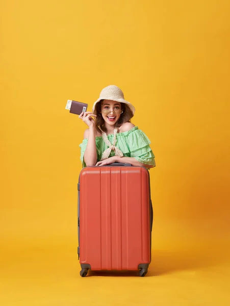 Joyeux jeune femme vêtue de vêtements d'été tenant passeport avec de l'argent tout étreinte avec valise isolée sur fond jaune . — Photo