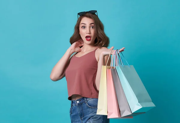 Porträtt av en upphetsad ung kvinna hand Holding shoppingväska isolerad över Blå bakgrund. — Stockfoto