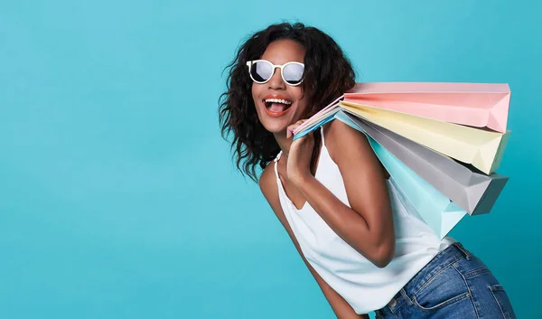 Retrato de una joven mujer africana emocionada sosteniendo la mano bolsa aislada sobre fondo azul . — Foto de Stock