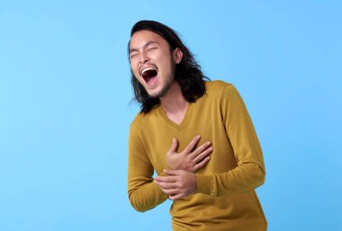 Asyalı genç adam mavi arka planda gülen yüz ile mutlu..