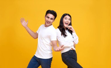 Gülümseyen Asyalı çift, mutlu ve şaşkın bir şekilde sarı arka planda..