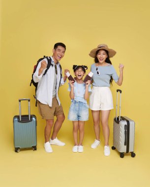 Mutlu Asya aile tatili portresi. Baba, anne ve kız seyahate hazır sarı stüdyo arka planında izole edilmiş..