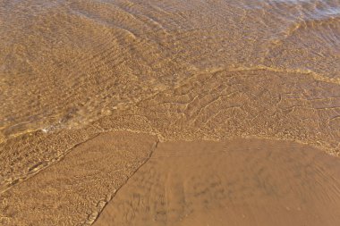 Yumuşak kum üzerine sığ açık su güzel güneşli küçük dalgalar