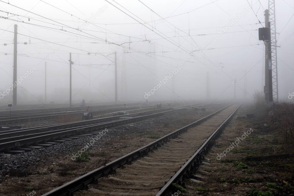 Crossing railways disappearing in the mist in autumn morning