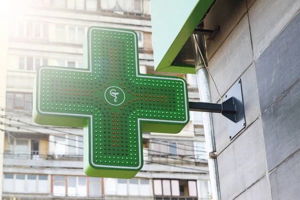 Green medical cross attached to the pharmacy building. Pharmacy Neon Sign. Green Cross sign on the building. Pharmacy concept. Drug store.