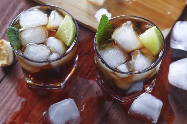 Rum buz ve limon ile. ROM ve cola Cuba libre kireç ve buz üzerinde ahşap üst bar.