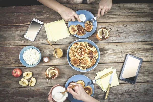 Top view of a pair of young people eating breakfast pancakes with sour cream on wooden table. Delicious breakfast. top view. rustic style