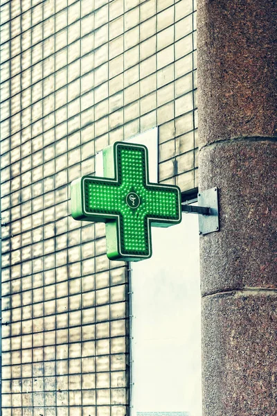 Green medical cross attached to the pharmacy building. Pharmacy Neon Sign. Drug store. Green Cross sign on the building. Pharmacy concept.