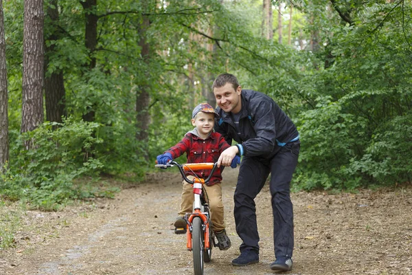 father teaches son to ride the bicycle. Safety, sports, leisure with kids concept.
