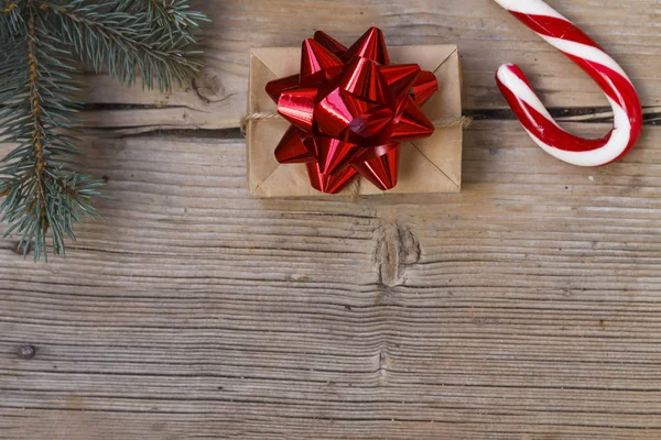 新年礼物在一个自制的盒子与红色弓附近毛茸茸的云杉分支和圣诞糖果手杖 复制空间 顶部视图 — 图库照片
