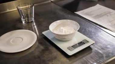 Ekmek. Mutfak terazisi ve tarifi üzerinde beyaz bir kasede un. Yemek. Şekerlemeler. Ekmek yapım ürünleri