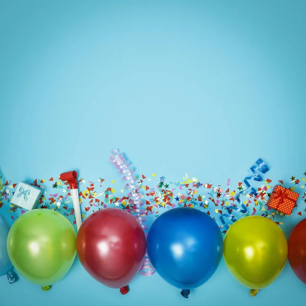 Multicolor party or birthday background on blue with a frame of colorful party balloons, streamers, confetti and candy around central copy space