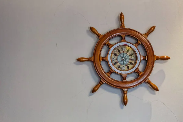 Concept: travel, sea navigation. Ship\'s nautical steering wheel and old compass on a light background with copy space.